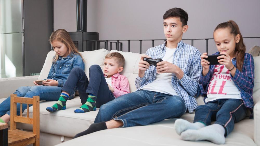four kids using gadgets representing less social life without summer camp