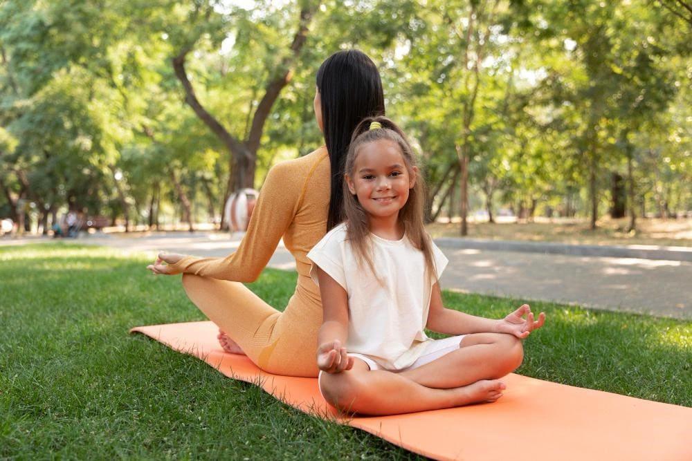 A small girl child with her mother doing yoga representing how meditation helps kids focus