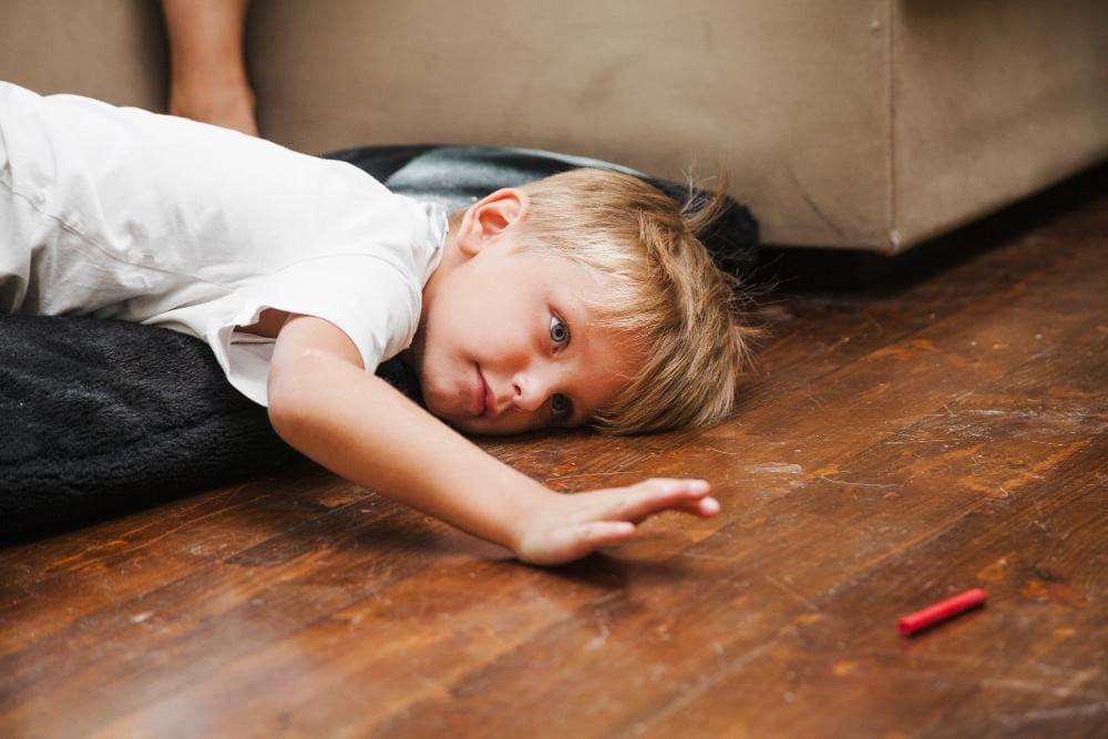 Outdoor Fitness Games for Kids That Actually Tire Them Out 1 Kids with white hair and white shirt laying on ground feeling tired without outdoor fun games